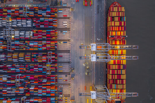 Corringham, England, United Kingdom - 25 September 2026: Aerial view of London Gateway port with a container ship docked alongside rows of colorful shipping containers and cranes.