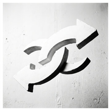 Minimalist black and white conceptual art featuring two interlocking white arrows on a textured wall symbolizing connection and flow.