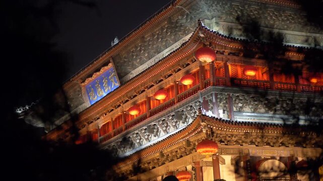 Illuminated traditional Chinese bell tower at night with glowing red lanterns and golden roof, historic city landmark in, festival decoration