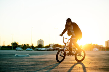 Naklejka premium Balance, BMX and flare with man on bike in city for activity, adrenaline hobby or sports training. Exercise, ride and risk with extreme person on bicycle on street for action, cycling or energy