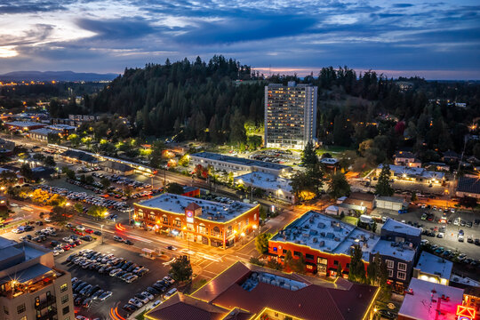 Eugene, Oregon, United States - 26 September 2026: Aerial view of downtown Eugene at dusk with city lights, urban development, and Skinner Butte Park rising above the city.