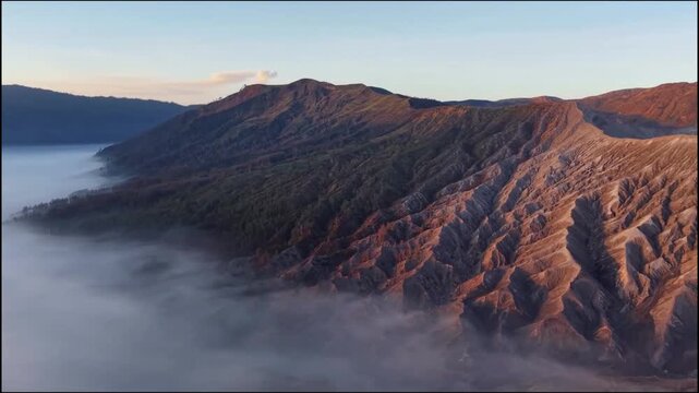 Aerial view of Mount Bromo crater smoking over sea of clouds at sunrise 
