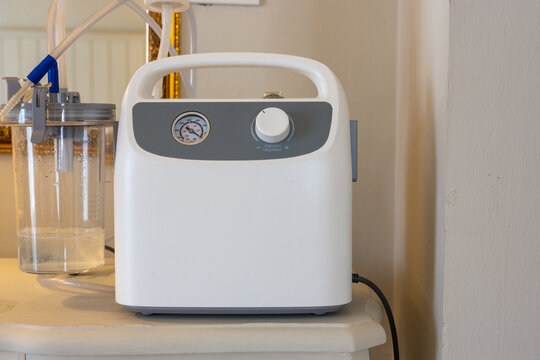 Portable Phlegm Suction, Sputum suction machine from a tube in the throat of a patient who has undergone a tracheostomy surgery in home.