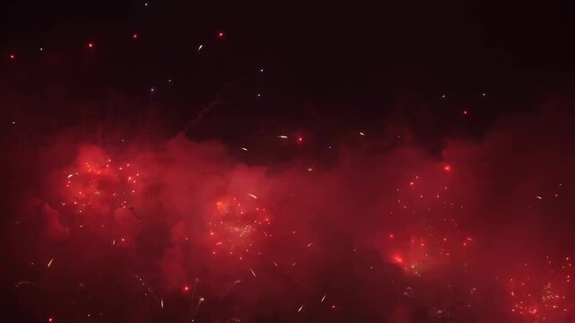Fireworks exploding in night sky with red and gold trails and smoke clouds