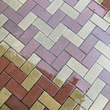 Herringbone brick paving with wet patches, pavement pattern background