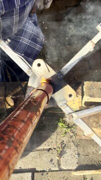 Vertical POV. Man using electrode with stick welding to join steel pieces