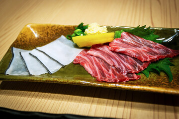 Closeup of kujira sashimi, or raw whale sushi featuring dark red akami whale meat taken from muscle tissue, and translucent white skin blubber shirokawa with a dark edge. It's a rare delicacy in Japan © ronniechua