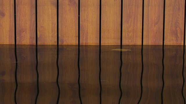 Wood Panel Wall Reflected in Still Dark Water, Vertical Grain Texture with Floating Leaf
