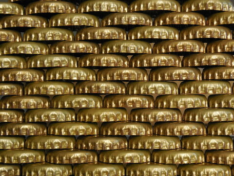 Pattern of golden metal beer bottle caps stacked in rows. Shiny gold crown caps texture background for brewing concept. Patr&oacute;n de chapas doradas de metal para botellas alineadas en filas.