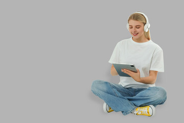Young woman sits cross-legged and smiles while using tablet with headphones © Atlas