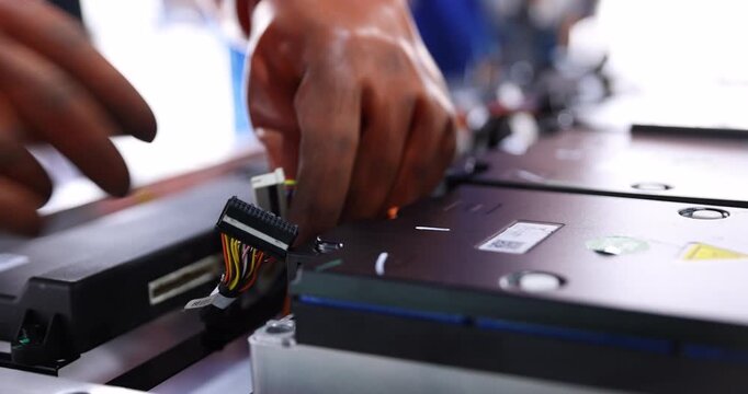 Close-up of a technician wearing orange gloves handling multipin wiring harness connectors inside an electric vehicle battery pack.