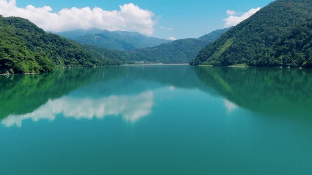 Aerial drone footage over the Wushe Reservoir in Taiwan, capturing reflections of clouds on the calm reservoir surface 