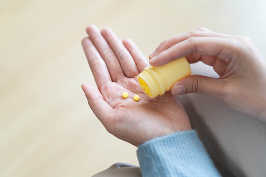 Person holding vitamin supplement pill and fresh water getting ready to swallow.