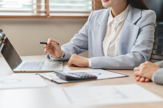 Financial advisors auditing data charts at office desk.