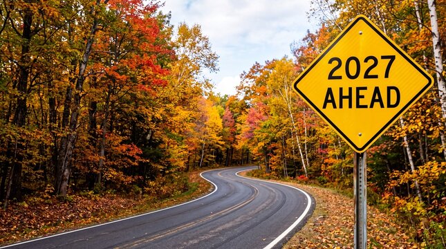 Winding forest road in autumn with a 2027 ahead traffic sign