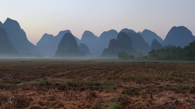 Aerial view of the iconic karst mountains rising above mist-covered harvested rice fields in Guilin, Guangxi, China.