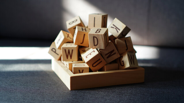 A stack of wooden alphabet letter blocks isolated on a dark grey background.