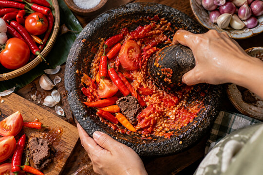 Traditional Indonesian Sambal Ulek Ground by Hand with Fresh Chilies and Tomato in Stone Mortar