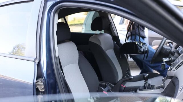 Young woman getting into the driver's seat of a car, placing her handbag inside and preparing to drive. Everyday transportation, commuting, personal mobility and modern lifestyle