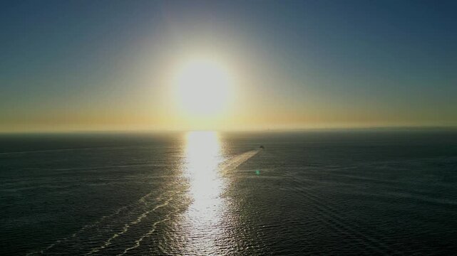 Aerial view from sunrise over the Tejo River as a ferry crosses the golden reflection of the sun, creating a dramatic silhouette against the calm morning waters.Lisbon,Portugal