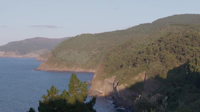 Rugged coastline of San Juan de Gaztelugatxe featuring steep cliffs, green hills, and the calm Cantabrian Sea