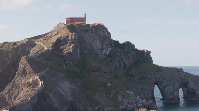 Historic hermitage on a rugged island connected by a winding stone bridge. Famous landmark attracting pilgrims and tourists