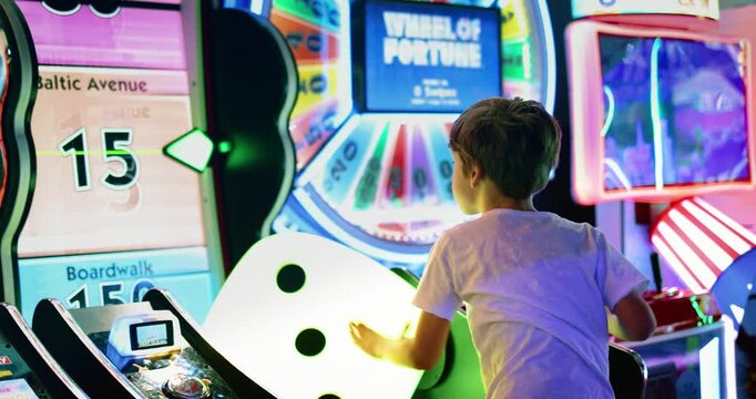 Young Boy Playing Arcade Game Surrounded by Colorful Neon Lights