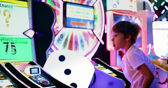 Young Boy Playing Arcade Game Surrounded by Colorful Neon Lights