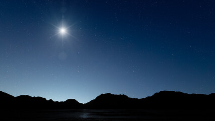 Fototapeta premium Glowing Christmas star above a peaceful mountain landscape