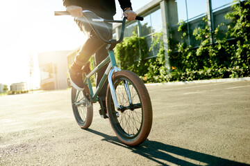 Naklejka premium BMX, legs and bicycle in city for exercise, eco friendly travel and cycling with hands. Person, riding bike and cyclist on road outdoor for fitness, sports and balance on urban street with flare
