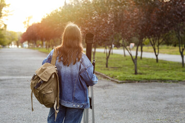 Fototapeta premium Astronomy and science education, young woman with telescope and backpack exploring nature and stargazing in a park during golden hour sunset
