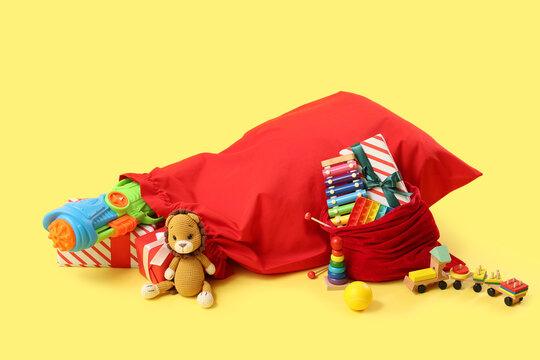 Christmas gift delivery, Santa Claus red sack filled with toys and presents for children on a yellow background