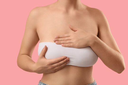Breast cancer awareness and self examination, woman checking for lumps for early detection and health screening on a solid pink background
