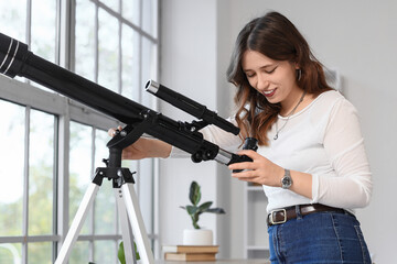 Fototapeta premium Astronomy and scientific discovery, young woman using a telescope for stargazing and space exploration in a bright home office with natural light