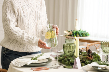 Holiday hospitality and festive dining, person serving lemon water at a decorated Christmas table...