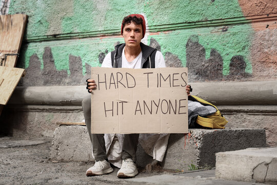 Homelessness and poverty crisis, young man holding a sign for help on a city street during economic hardship and social inequality in an urban environment