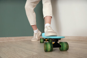 Fototapeta premium Urban lifestyle and youth culture, person standing on a blue plastic skateboard wearing casual sneakers and trousers in a modern home interior