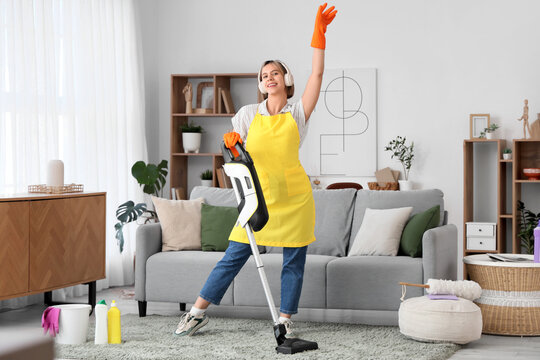 Housework and cleaning motivation, happy woman with vacuum cleaner and headphones dancing in living room while doing chores at home