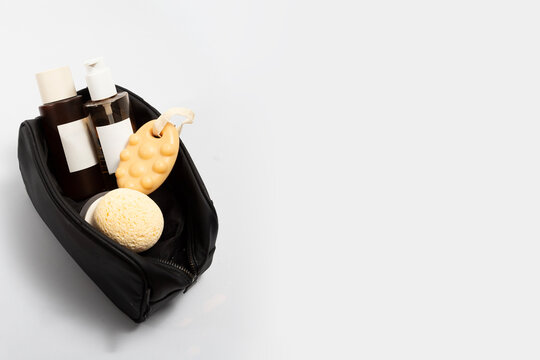 Black travel pouch filled with oil cleanser bottle ,foam clean tube, toner lotion, cream jar, solid shampoo and sponge . Ideal for a clean skincare routine on the go and modern travelers.