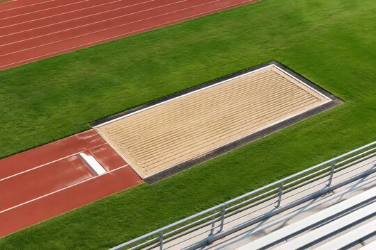 Long jump sand pit freshly raked in precise parallel furrows with fine grain texture