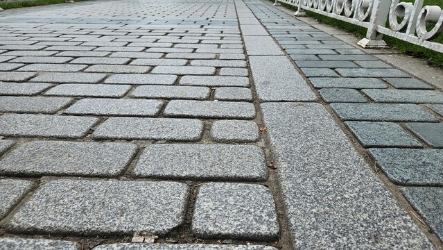 Close View of Gray Granite Paving Stones Along Park Path with Ornamental Fence