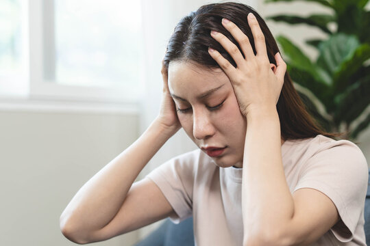 Asians female in stressed expression sitting on the sofa in the house.