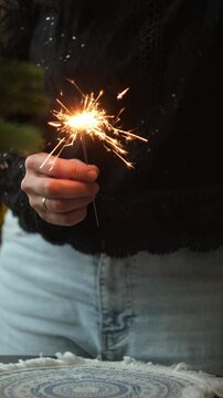 Vertical video. Happy New Year party. Woman dancing celebrating New Year holding glass of champagne and sparkler in her hand