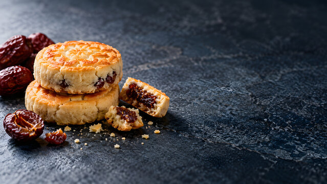 Delicious shortbread cookies filled with sweet red dates, placed on dark textured surface, evoke sense of indulgence and warmth