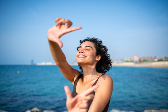 Woman framing sea view with hands enjoying summer in Barcelona