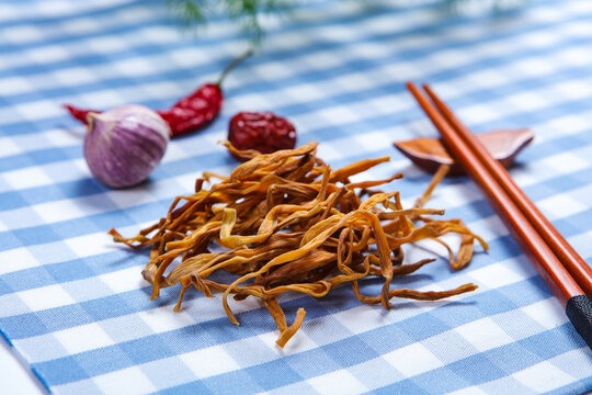 Dried Daylily Flowers On Glass Plate Over Wooden Cutting Board