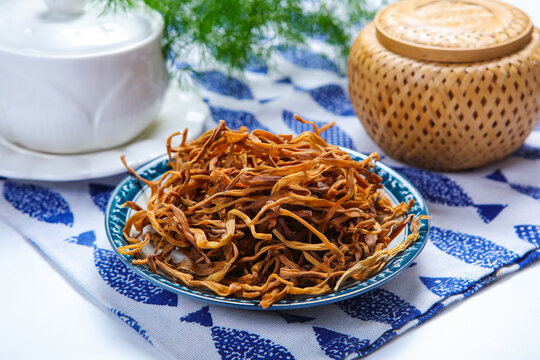 Dried Daylily Flowers On Glass Plate Over Wooden Cutting Board