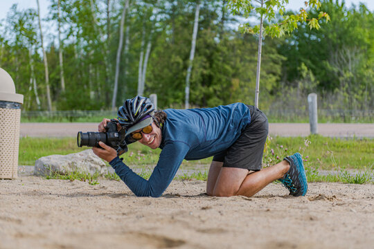 Cyclist photographer kneels on the sand for a low angle shot