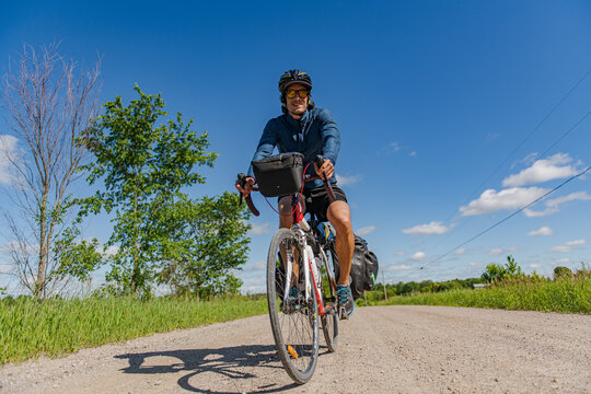 Smiling man riding a touring bike on a gravel road