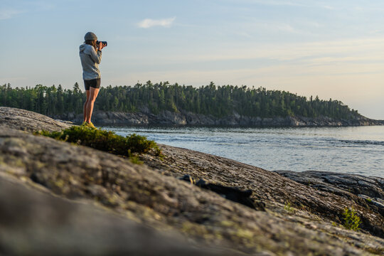 Photographer standing on rocks taking pictures of a lake